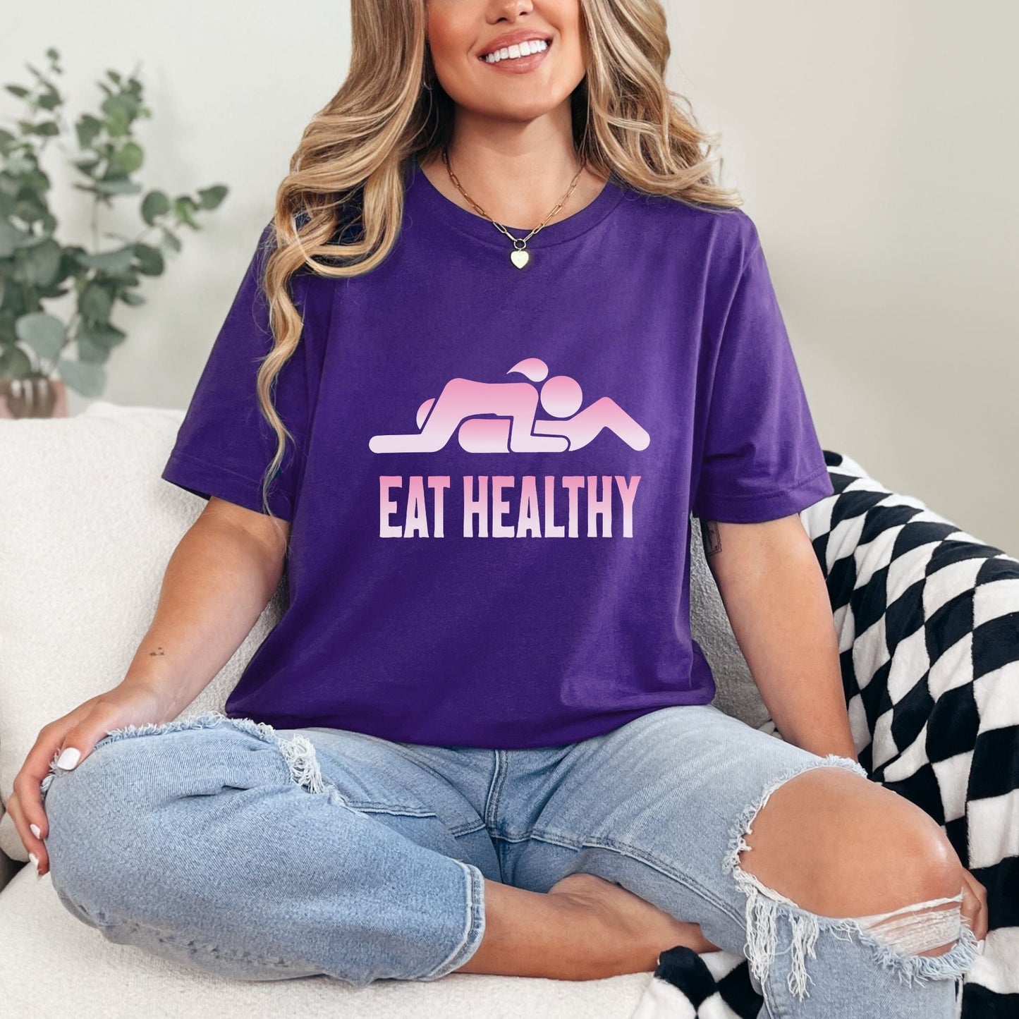 a woman sitting on a couch wearing a purple shirt that says eat healthy