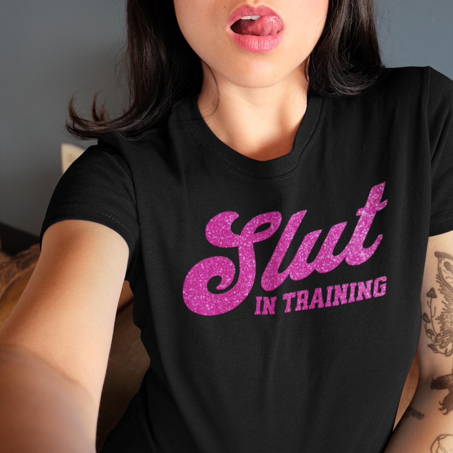 a woman wearing a black shirt with pink glitter in the letters slut in training