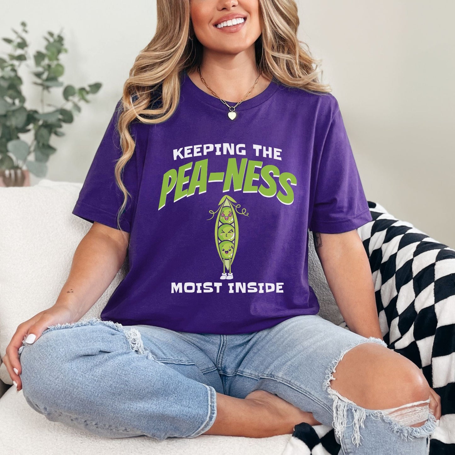 a woman sitting on a couch wearing a purple shirt