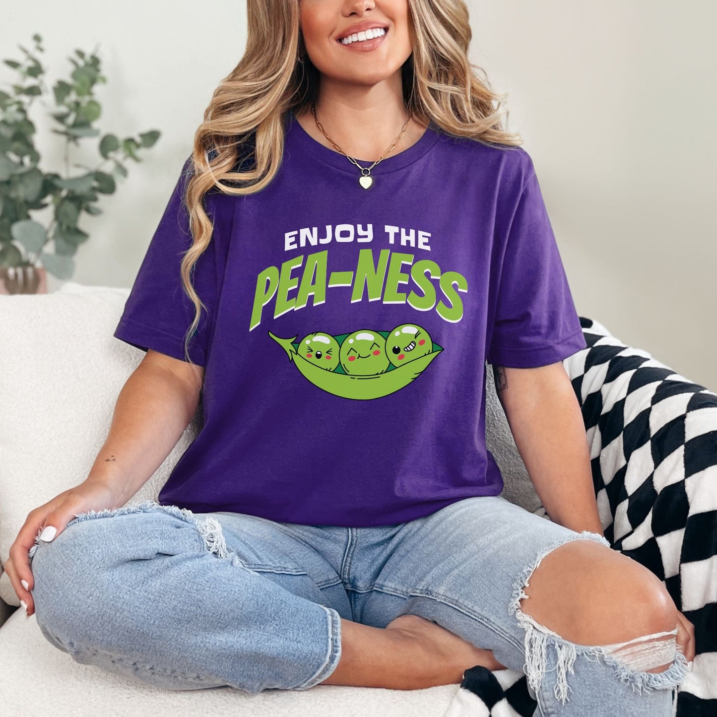 a woman sitting on a couch wearing a purple shirt