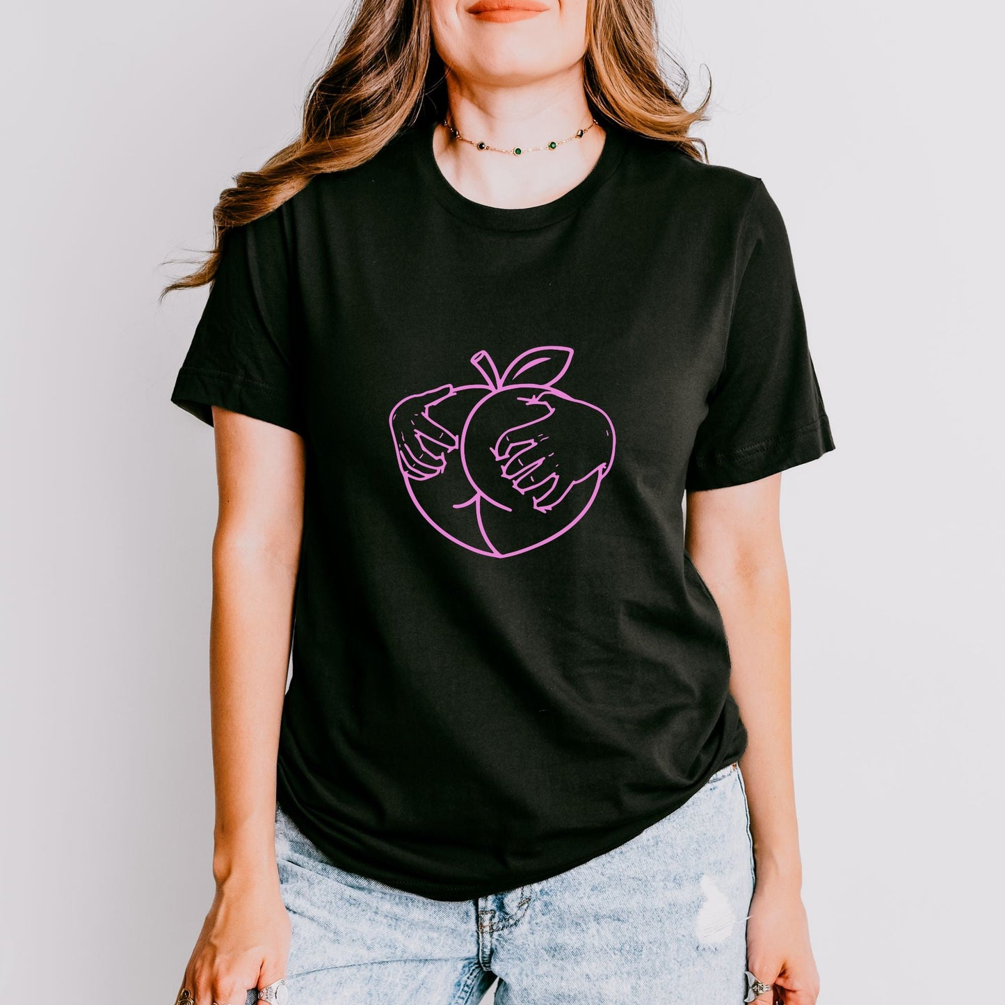 a woman wearing a black shirt with a pink apple on it