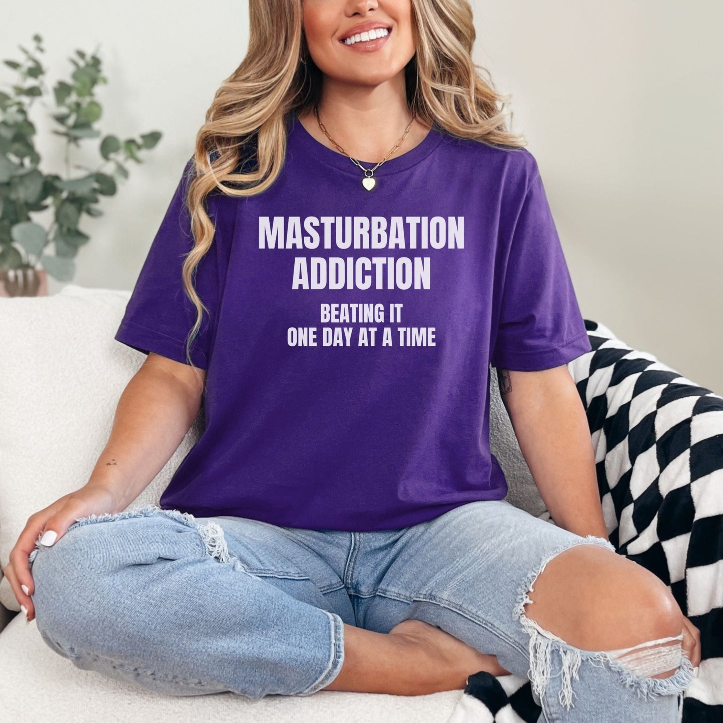 a woman sitting on a couch wearing a purple shirt