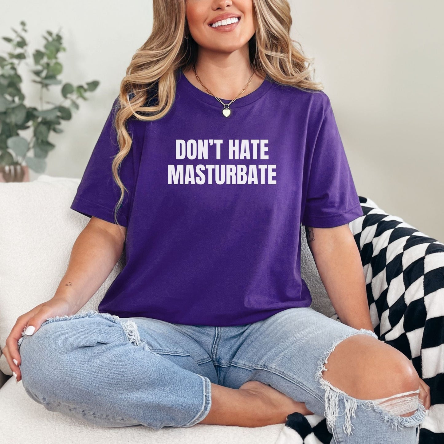 a woman sitting on a couch wearing a purple shirt that says don't hate