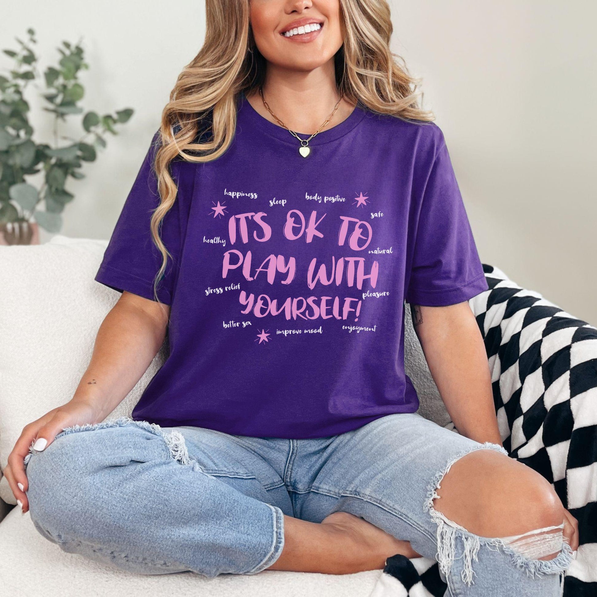 a woman sitting on a couch wearing a purple shirt